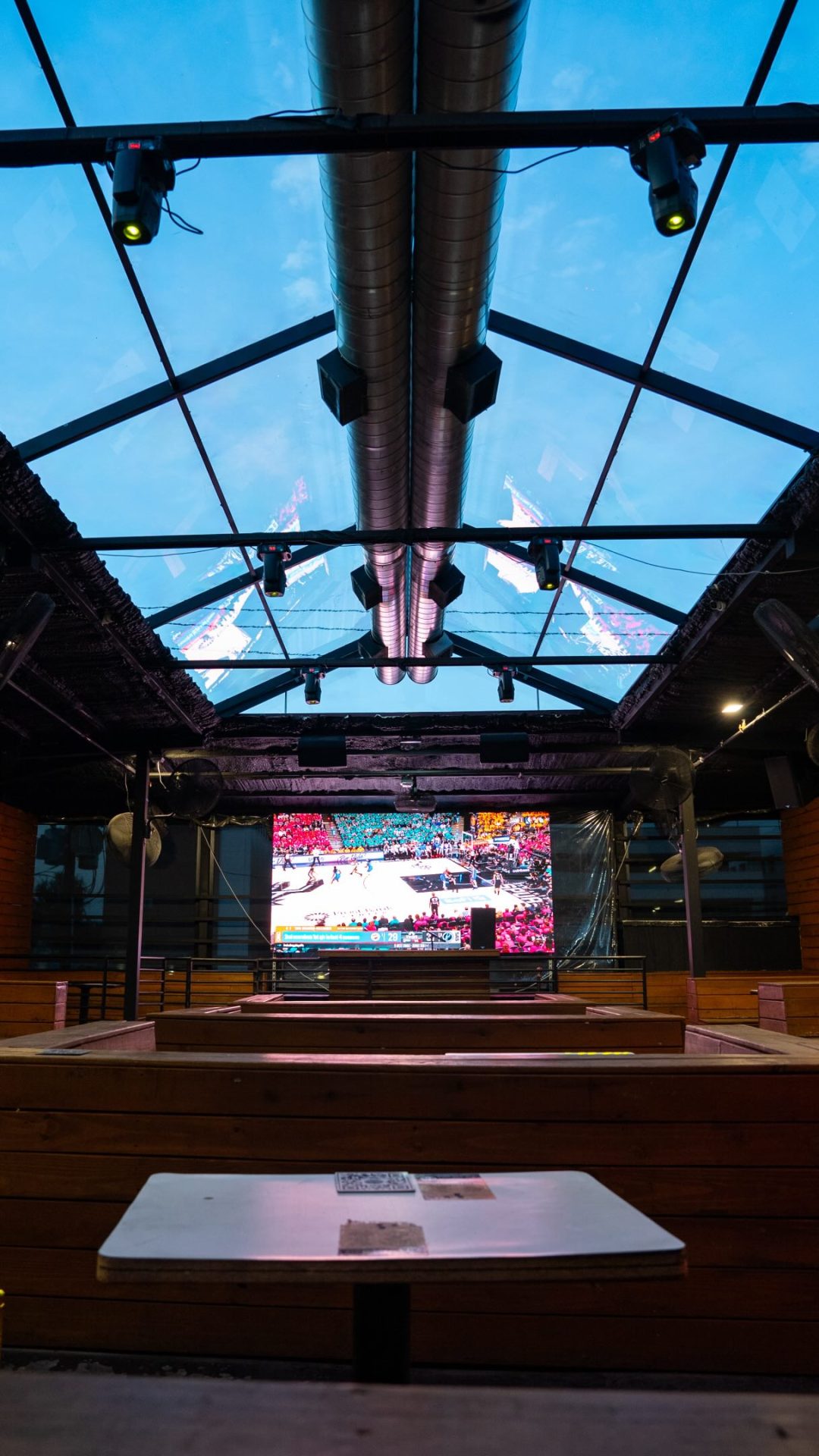 Glass-roofed rooftop deck with big screen at Privilege Houston